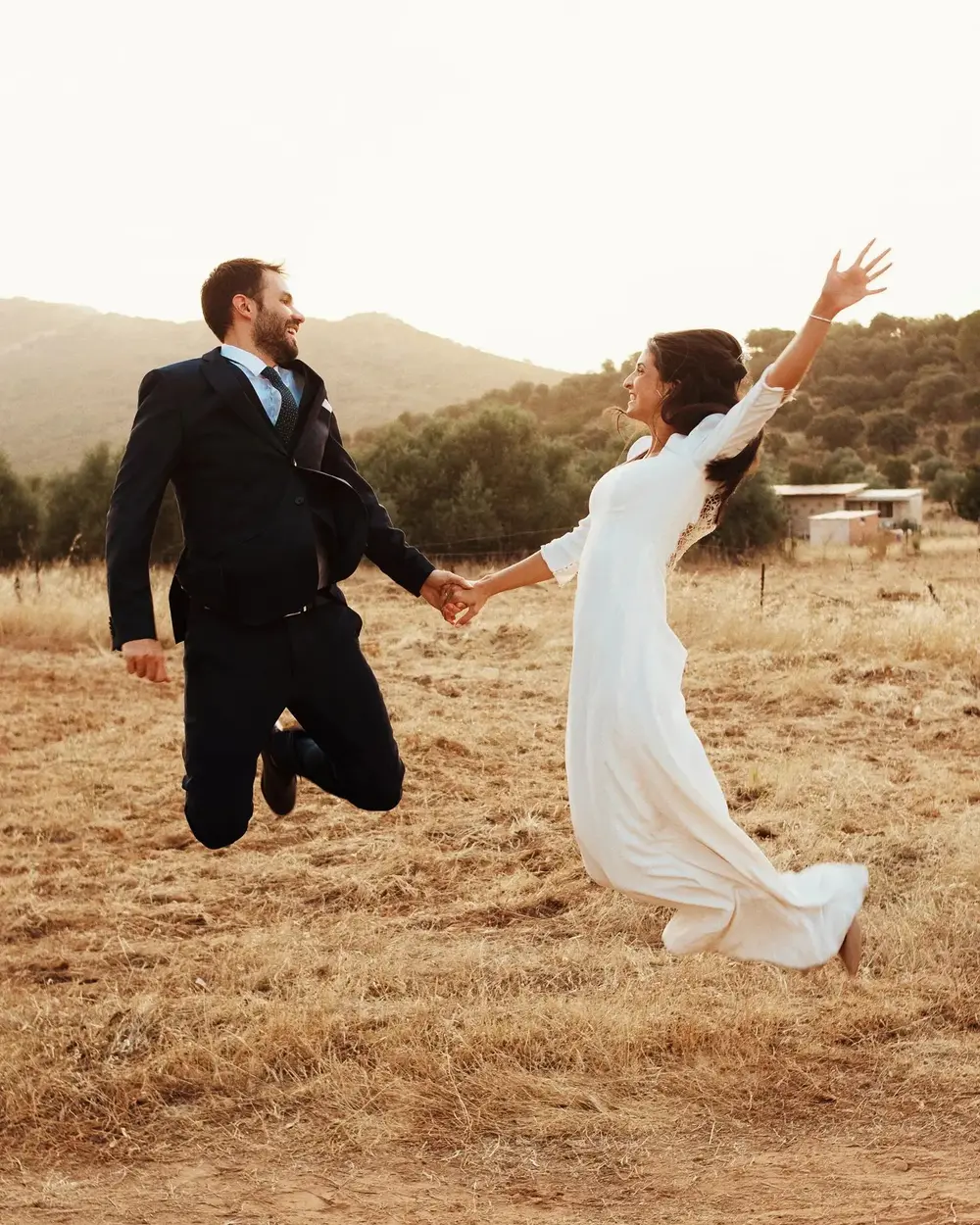 María y Tito saltando de la mano en el campo